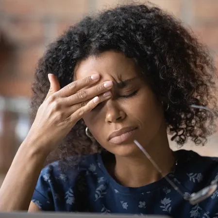 Woman With Headache Holding Her Glasses and Rubbing Her Forehead